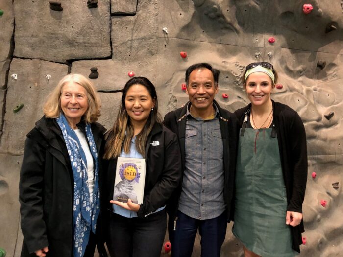 The author poses with three other people in a rock climbing gym.