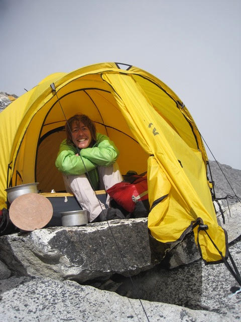 Dr. Piris smiles from inside her tent, planted on rocky ground.