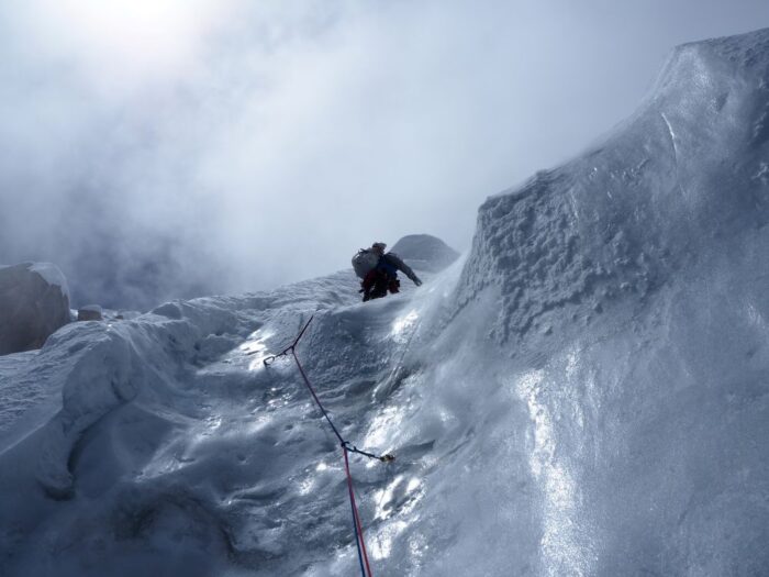 A climber on the top of a vertical ice section.