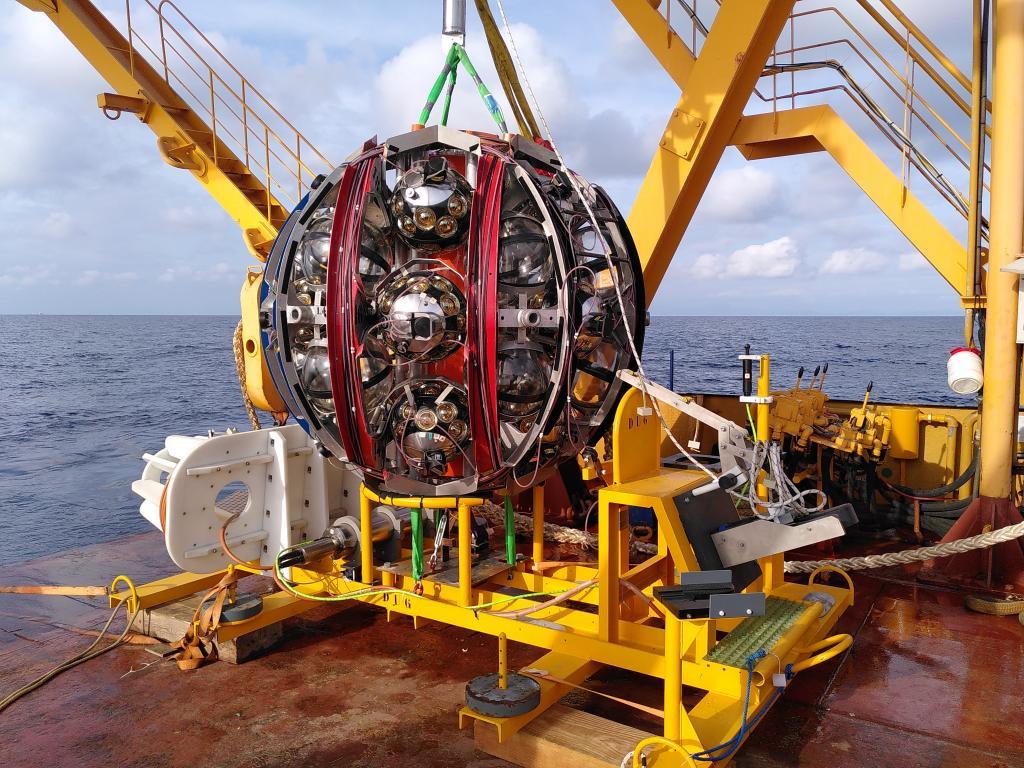 A large metal sphere suspended by a crane.
