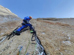The climber on aid-climbing gear to pass a crack on otherwise smooth granite.