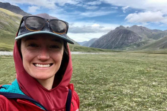 Chelsey is wearing a sun shirt with the hood pulled up. The mountains of ANWR are behind her.