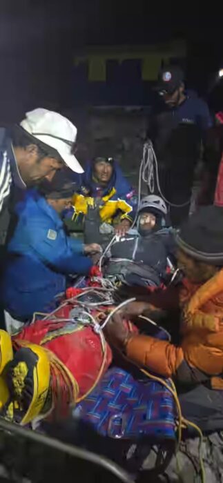 Pakistanis surrounding an injured climber tied to a stretcher.