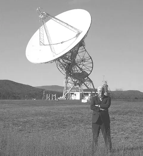 A man standing in front of a radio telescope.